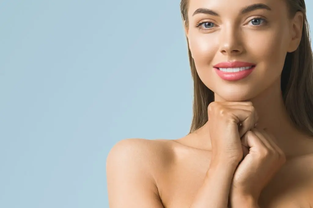 Woman portrait skin care long beauty brunette hair hand manicure touching face blue background